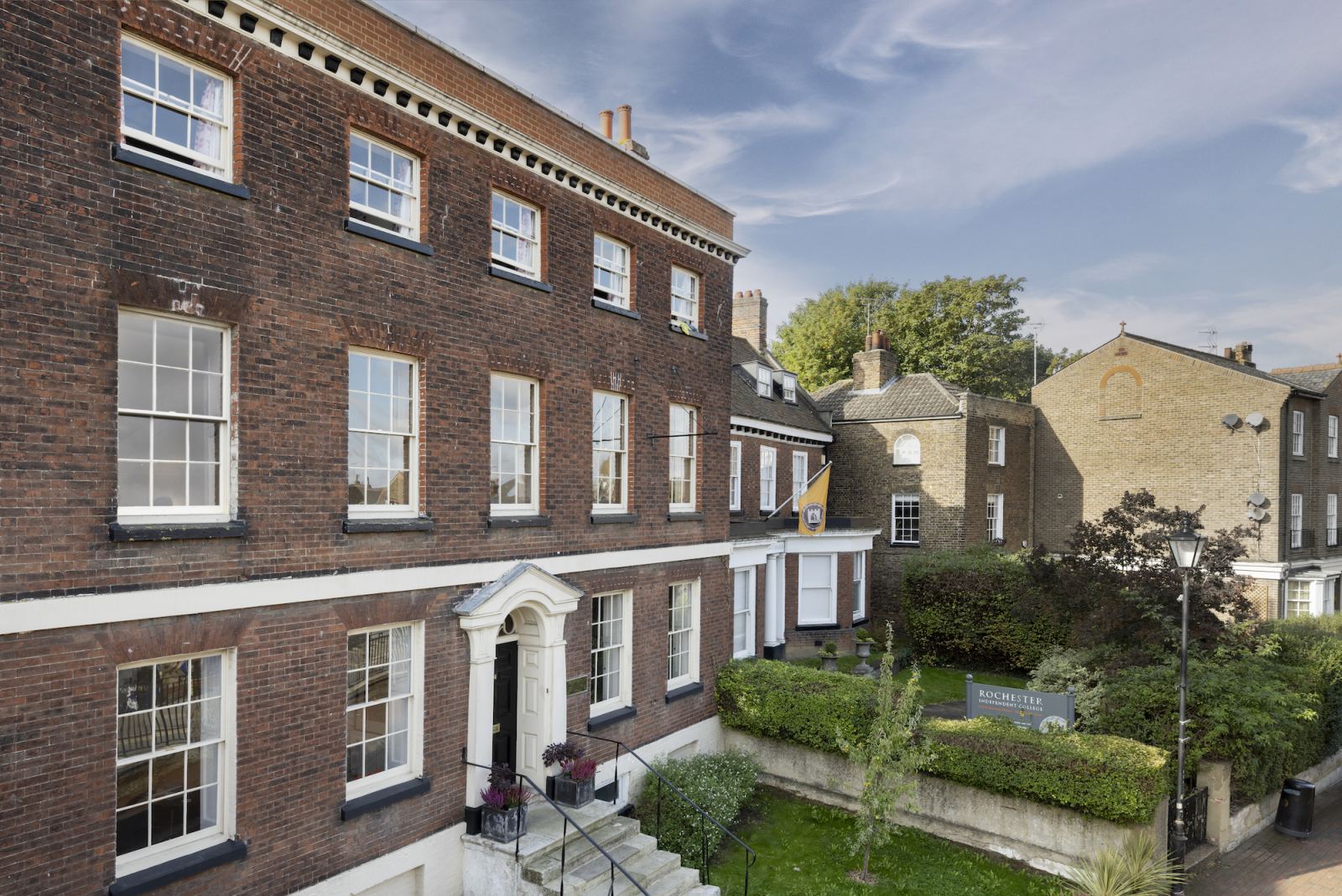 The brick frontage of Rochester Independent College, with its drive and gardens